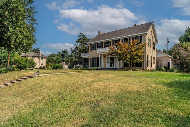 colonial house featuring a balcony and a front lawn