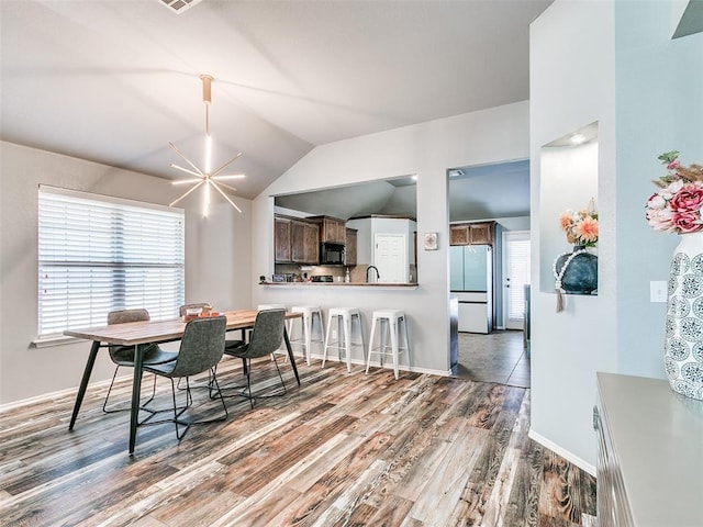 dining space featuring hardwood / wood-style flooring, an inviting chandelier, lofted ceiling, and sink