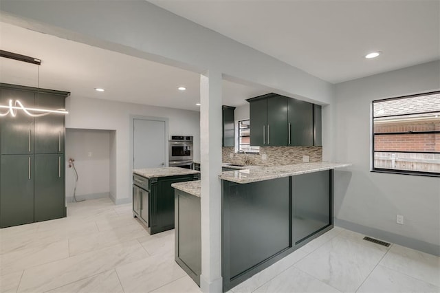 kitchen featuring pendant lighting, sink, tasteful backsplash, light stone counters, and kitchen peninsula