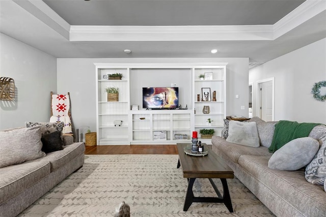 living room with a raised ceiling, wood-type flooring, and ornamental molding