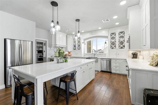 kitchen featuring pendant lighting, a kitchen breakfast bar, appliances with stainless steel finishes, tasteful backsplash, and white cabinetry