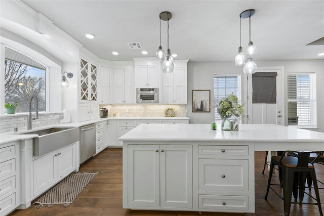 kitchen featuring sink, hanging light fixtures, tasteful backsplash, white cabinets, and appliances with stainless steel finishes