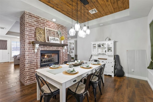 dining room featuring a tray ceiling, a fireplace, wood ceiling, and dark hardwood / wood-style floors