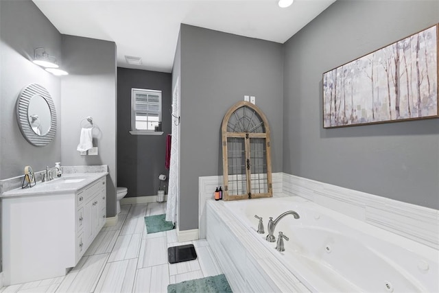 bathroom featuring vanity, tiled bath, and toilet