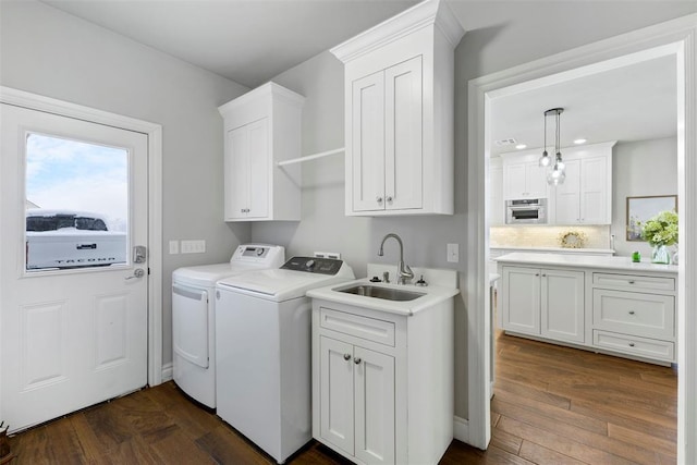 laundry area featuring washer and clothes dryer, cabinets, sink, and dark wood-type flooring