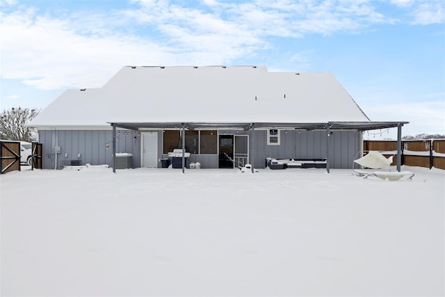 snow covered rear of property featuring central AC