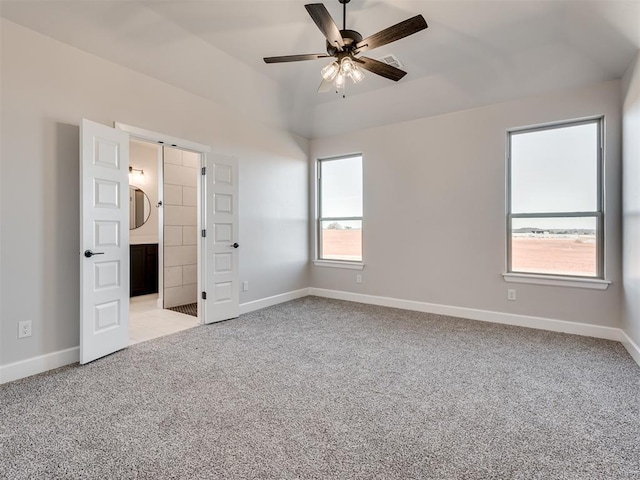 unfurnished bedroom featuring ensuite bath, ceiling fan, light carpet, and lofted ceiling