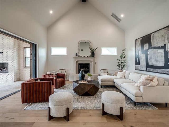 living room with beam ceiling, light wood-type flooring, high vaulted ceiling, and a wealth of natural light