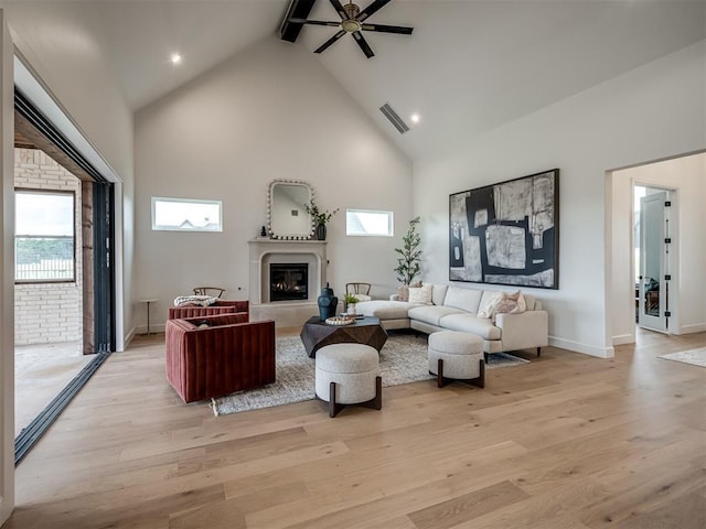 living room with ceiling fan, beamed ceiling, light hardwood / wood-style floors, and high vaulted ceiling