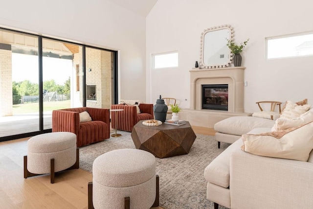 living room with a fireplace, high vaulted ceiling, and light hardwood / wood-style flooring