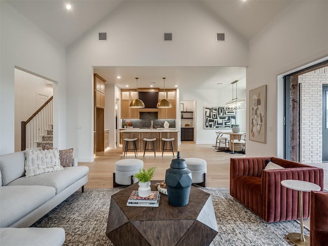 living room featuring light hardwood / wood-style flooring, high vaulted ceiling, and sink