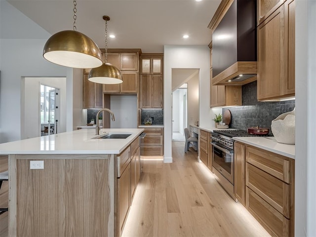 kitchen with backsplash, wall chimney range hood, sink, high end stainless steel range oven, and hanging light fixtures