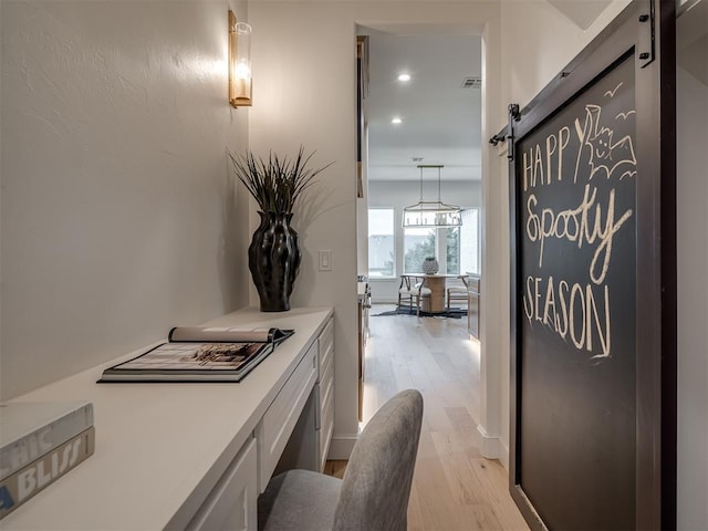 hallway with a barn door and light wood-type flooring