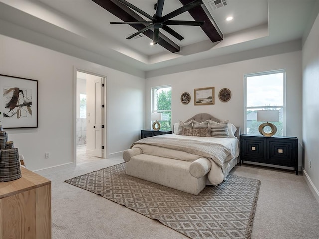 bedroom with light carpet, a tray ceiling, ensuite bath, and ceiling fan