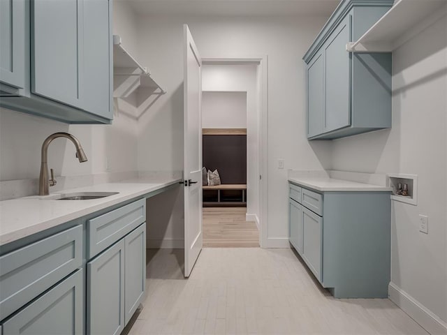 clothes washing area featuring cabinets, washer hookup, light hardwood / wood-style flooring, and sink