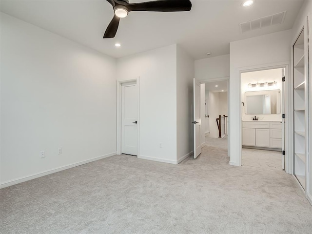 unfurnished bedroom featuring connected bathroom, light colored carpet, ceiling fan, and sink