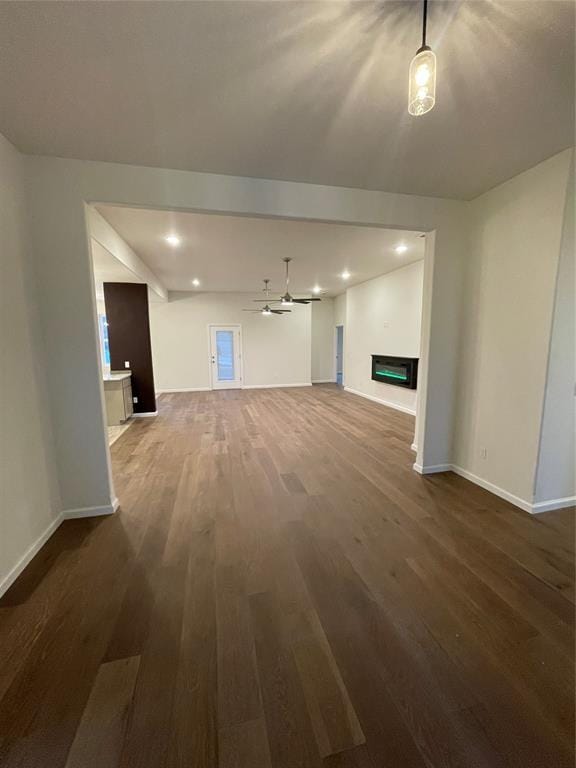 unfurnished living room featuring ceiling fan and dark wood-type flooring