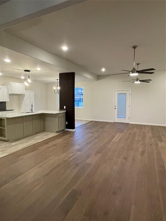 unfurnished living room featuring ceiling fan, dark hardwood / wood-style flooring, and sink