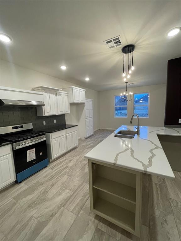 kitchen featuring sink, hanging light fixtures, stainless steel stove, an island with sink, and white cabinets