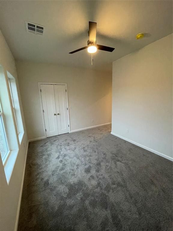 unfurnished room featuring ceiling fan and dark carpet