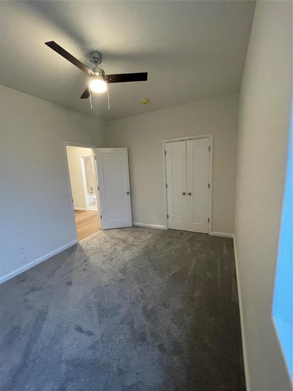 unfurnished bedroom featuring dark colored carpet, ceiling fan, and a closet