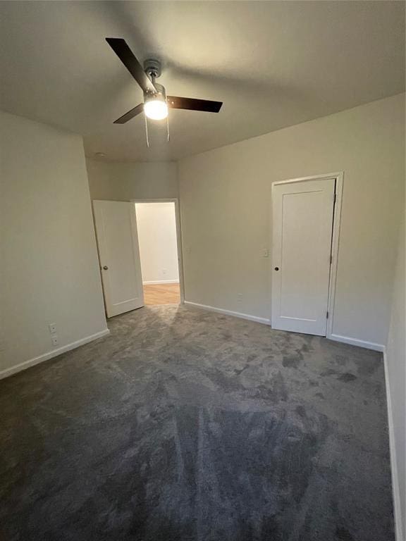 unfurnished room with dark colored carpet and ceiling fan