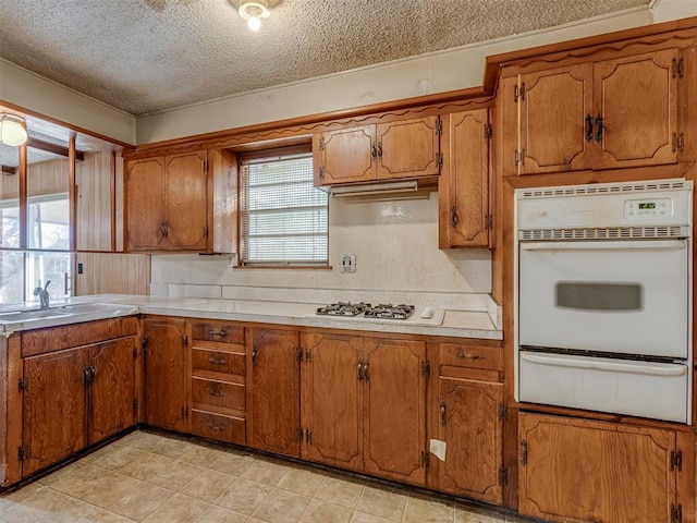 kitchen with a textured ceiling, sink, and white appliances