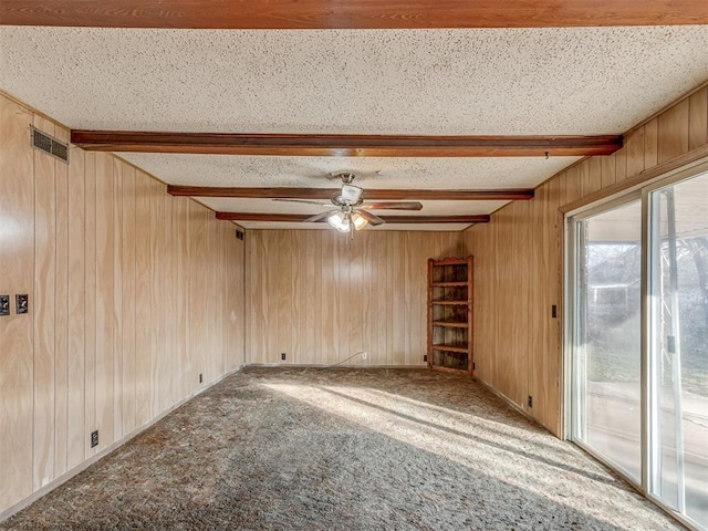 empty room with beam ceiling, carpet floors, a textured ceiling, and ceiling fan