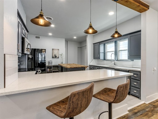 kitchen featuring sink, dark wood-type flooring, light stone counters, backsplash, and kitchen peninsula