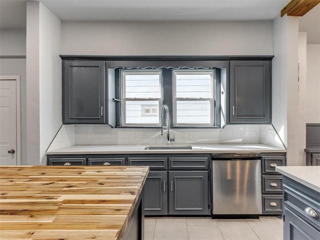 kitchen with light tile patterned floors, tasteful backsplash, stainless steel dishwasher, and sink