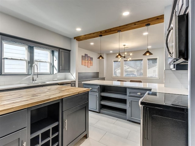 kitchen with pendant lighting, sink, tasteful backsplash, beamed ceiling, and range