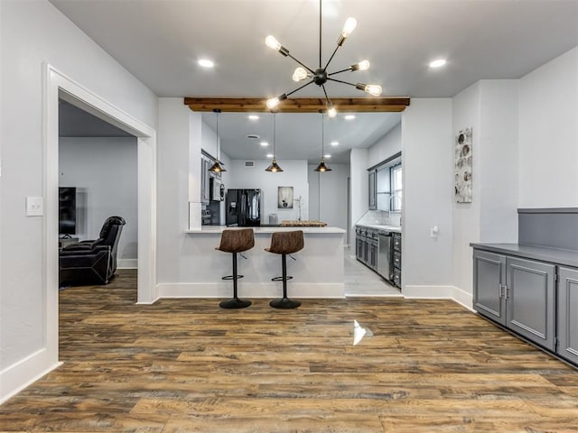 kitchen with black refrigerator with ice dispenser, kitchen peninsula, pendant lighting, gray cabinets, and a breakfast bar