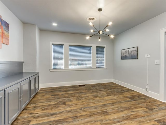 unfurnished dining area featuring dark wood-type flooring and a chandelier