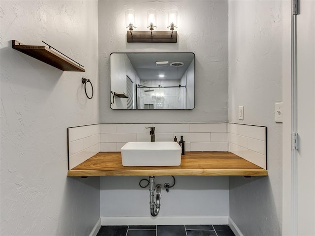 bathroom featuring decorative backsplash, tile patterned floors, and sink