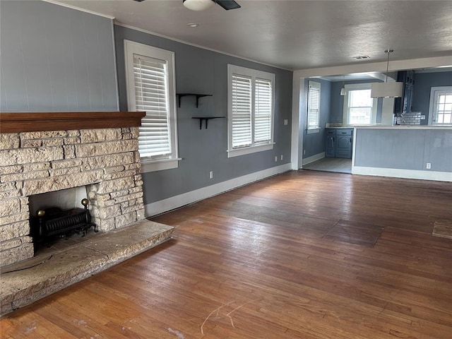 unfurnished living room featuring crown molding, a fireplace, dark hardwood / wood-style flooring, and ceiling fan