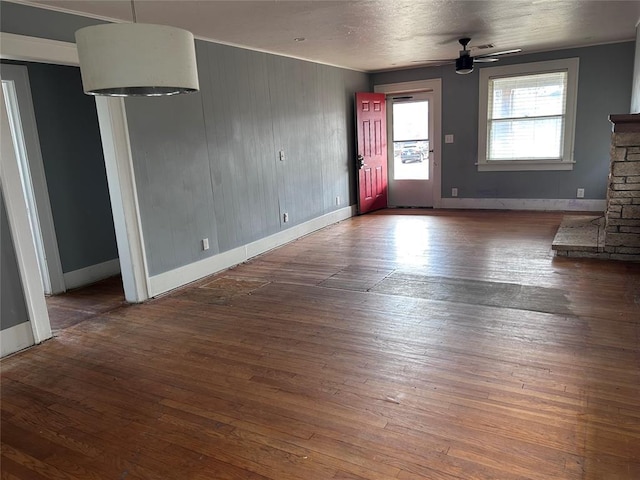 unfurnished living room with ceiling fan, a fireplace, and dark hardwood / wood-style flooring