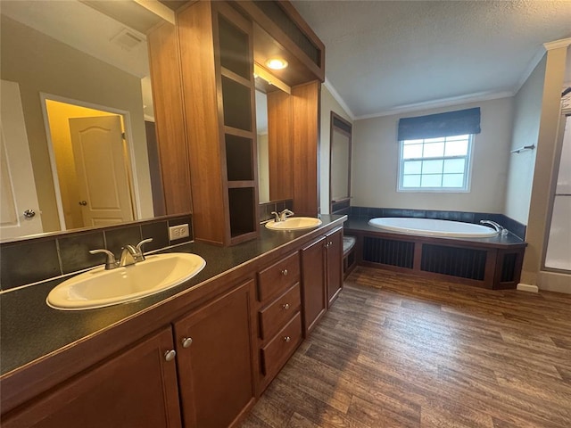 bathroom featuring a tub, crown molding, wood-type flooring, vaulted ceiling, and vanity