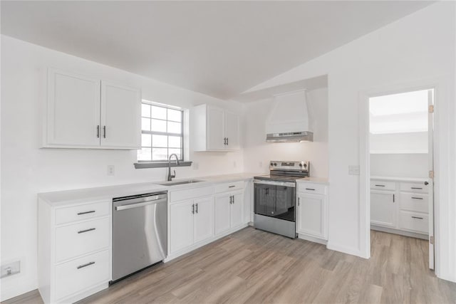 kitchen with white cabinetry, sink, stainless steel appliances, custom range hood, and light wood-type flooring