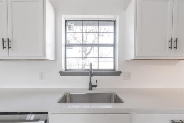 kitchen featuring light stone counters, sink, white cabinets, and stainless steel dishwasher