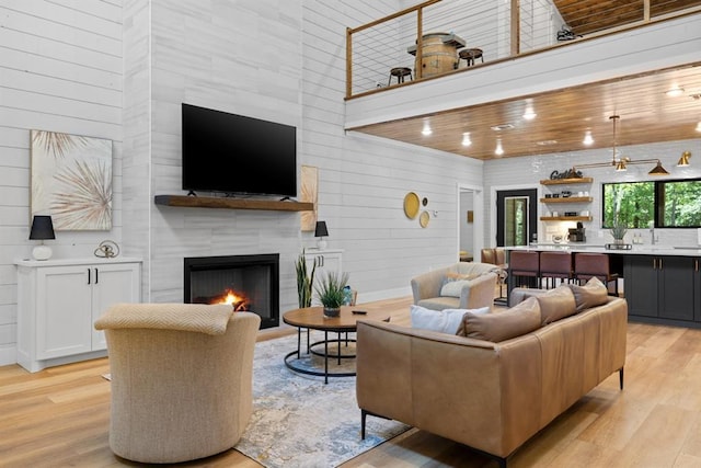 living room with a tiled fireplace, light hardwood / wood-style floors, and a high ceiling