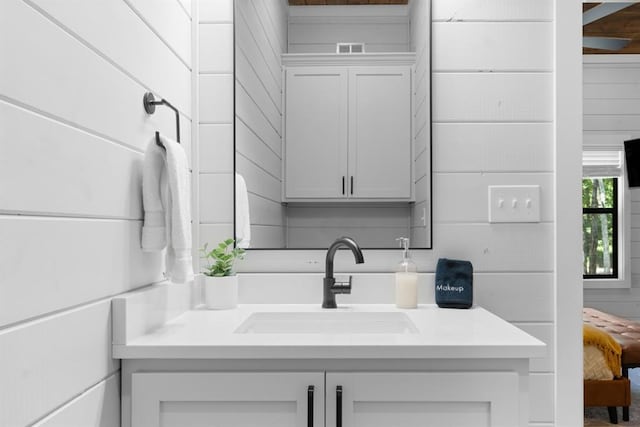 bathroom featuring vanity and wooden walls