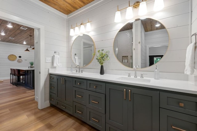 bathroom featuring hardwood / wood-style floors, vanity, wood ceiling, and wooden walls