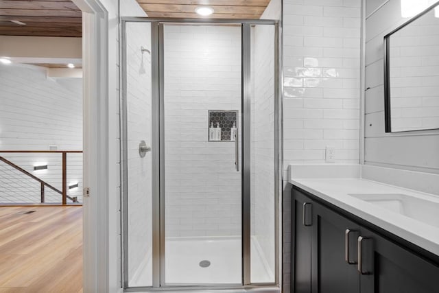 bathroom with hardwood / wood-style floors, vanity, a shower with door, and wooden ceiling