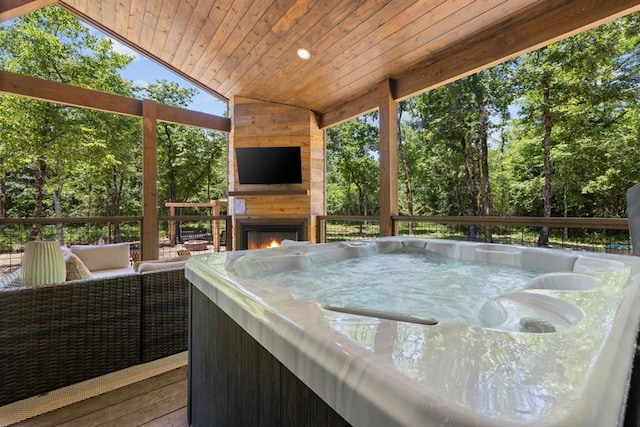 wooden terrace featuring a hot tub and an outdoor fireplace