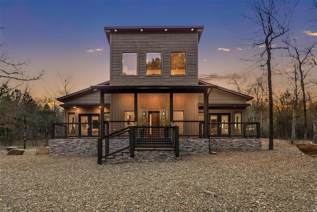 back of property at dusk with a porch and french doors