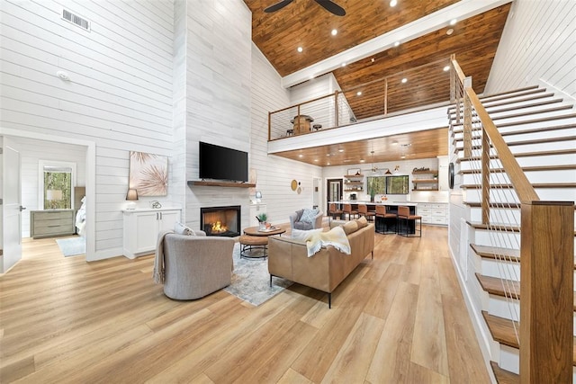 living area with wooden ceiling, high vaulted ceiling, light wood-type flooring, stairs, and a ceiling fan