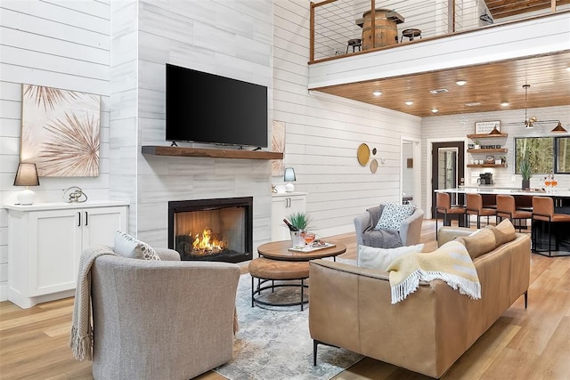 living area with wood walls, a large fireplace, recessed lighting, and light wood finished floors