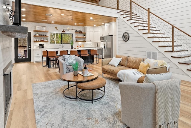 living room featuring stairway, visible vents, a tile fireplace, light wood-type flooring, and recessed lighting