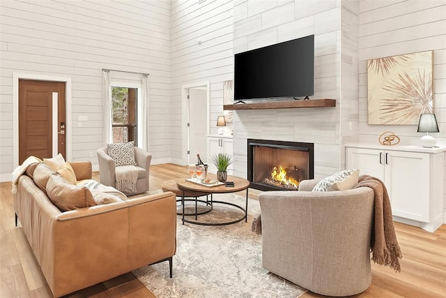 living area with a fireplace, a high ceiling, and light wood finished floors