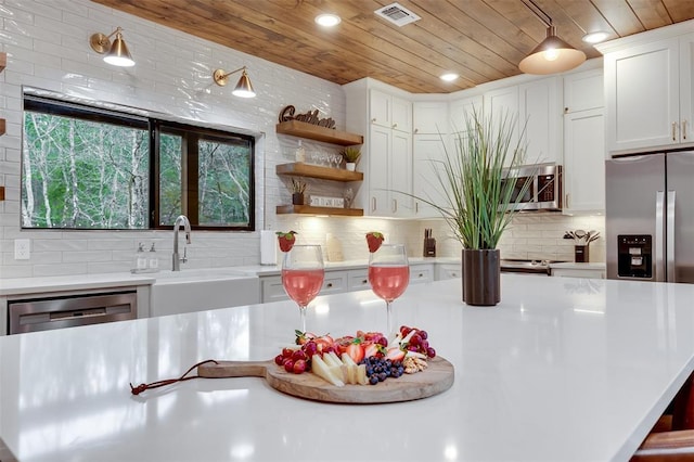 kitchen with wood ceiling, visible vents, stainless steel appliances, and a sink